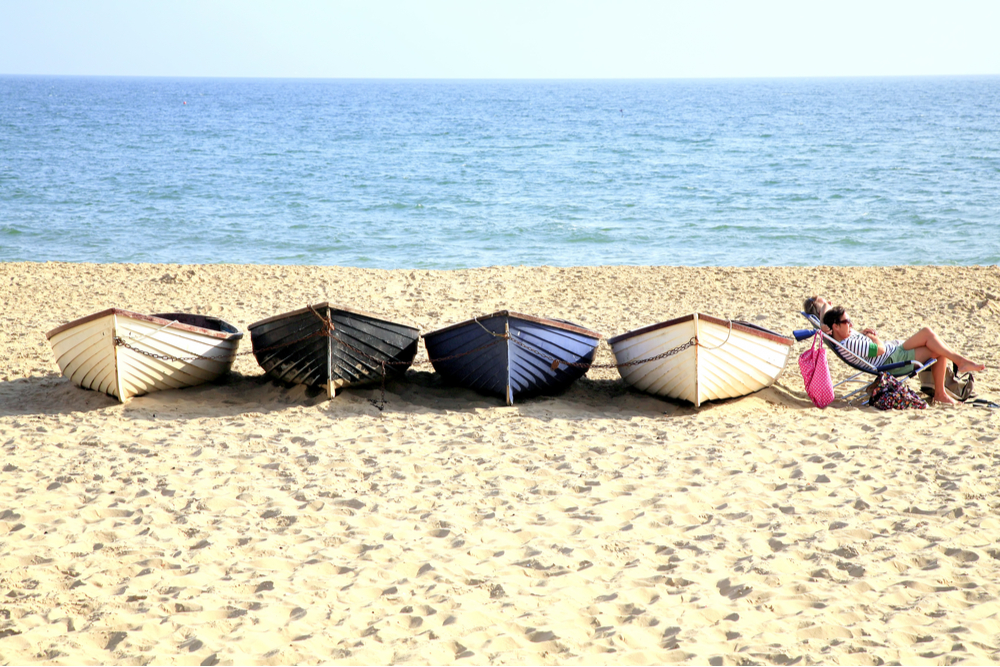 couple relax by row of boats on Bournemouth beach