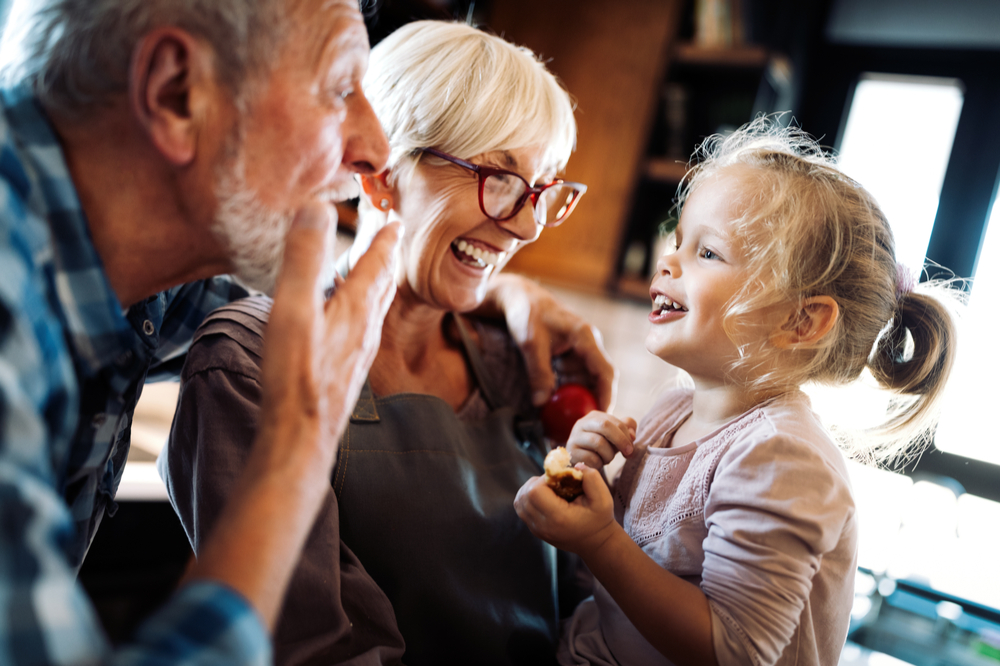 Happy smiling grandparents playing with their granddaughter