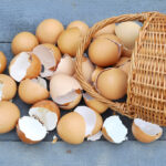 a basket full of broken eggs on a wooden background